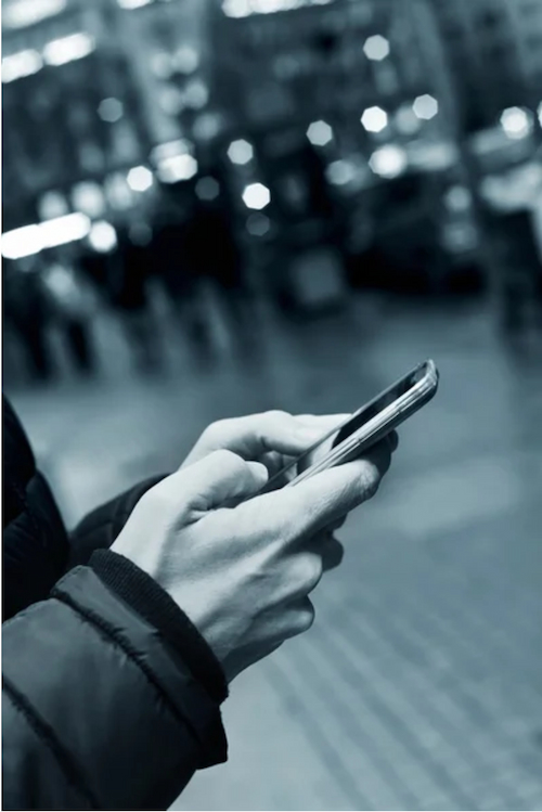 A person's hands holding a mobile phone, typing on it.